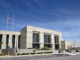 Banning Justice Center framed by manicured trees and bushes beneath a clear blue sky