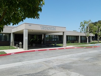 Riverside Juvenile Courthouse framed by manicured trees beneath a clear blue sky.